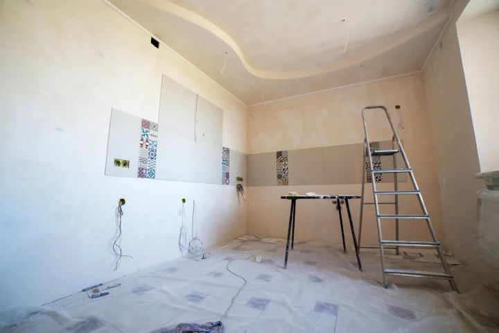 Pièce d’un logement ancien en cours de rénovation : murs enduits, câbles électriques apparents et échelle