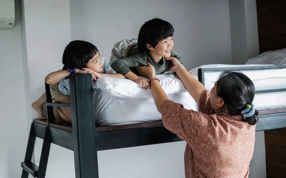 Deux enfants sur un lit superposé avec leur grand-mère dans une chambre partagée, illustration de la sur-occupation d’un logement