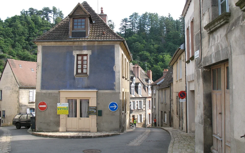 Maison de village avec un panneau à vendre sur la façade, à Aubusson (Creuse)