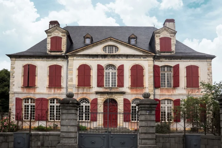 Façade d’une maison de maître avec perron, volets rouges et toit en ardoise