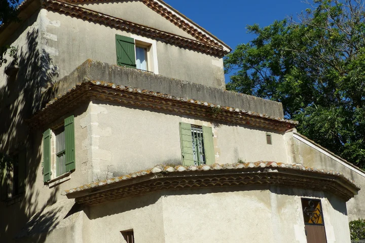 Façade provençale d'un mas à Méjanes, Saintes-Maries-de-la-Mer : enduit clair, volets verts et génoises en tuiles canal