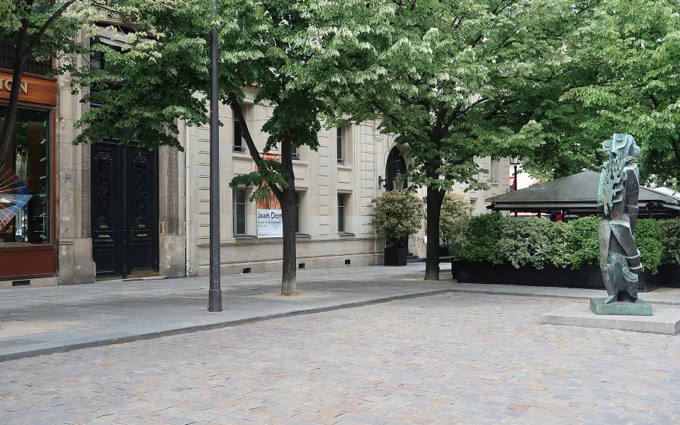Place Saint-Germain-des-Prés dans le 6e arrondissement de Paris, sous les arbres, avec une statue sur la droite