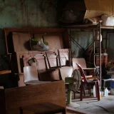 Vieux meubles en bois, chaises et panneaux entreposés dans un local de stockage