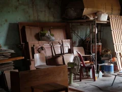 Vieux meubles en bois, chaises et panneaux entreposés dans un local de stockage
