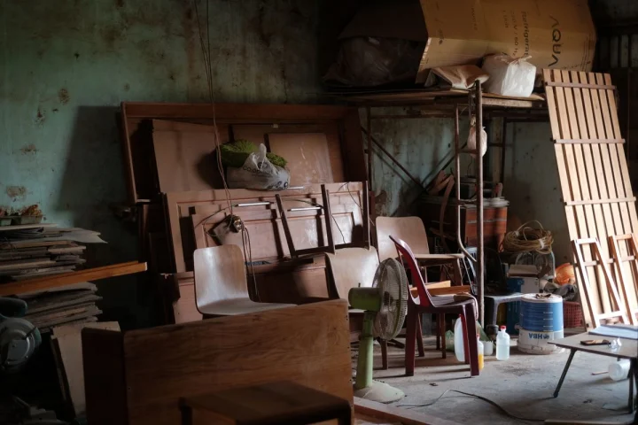 Vieux meubles en bois, chaises et panneaux entreposés dans un local de stockage