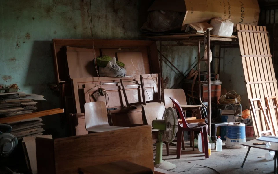 Vieux meubles en bois, chaises et panneaux entreposés dans un local de stockage